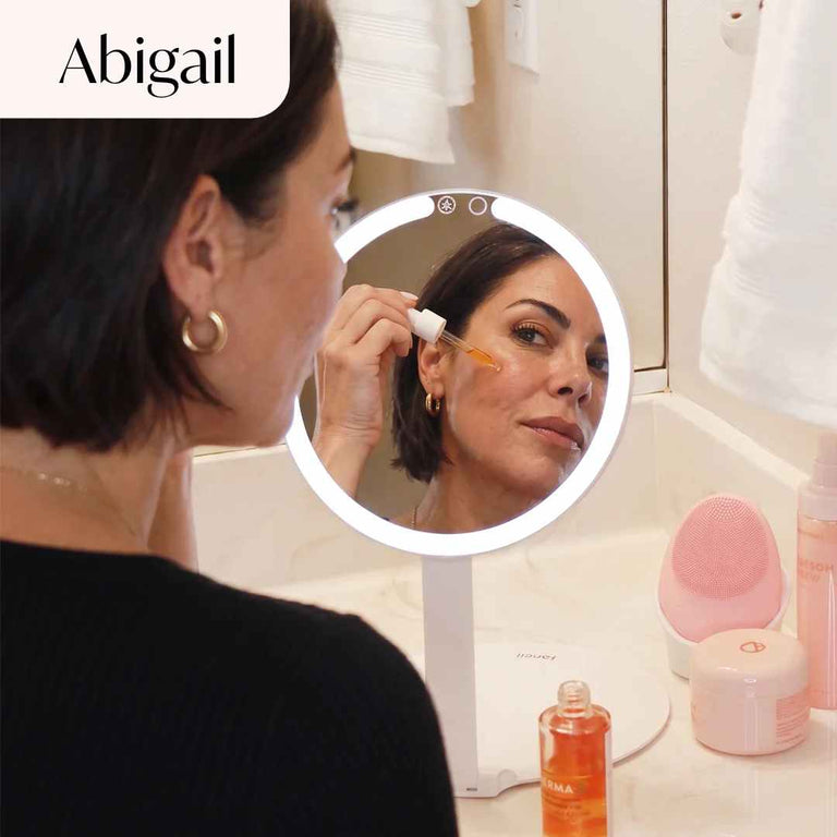 Abigail Lighted Compact in White Set up on desk and being used by model to apply lipstick