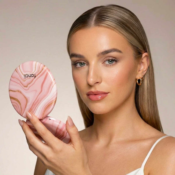 Taylor Lighted Compact Mirror with 10x Magnifying by Fancii & Co. open and lit up held by model in MARBLE ROSÈ