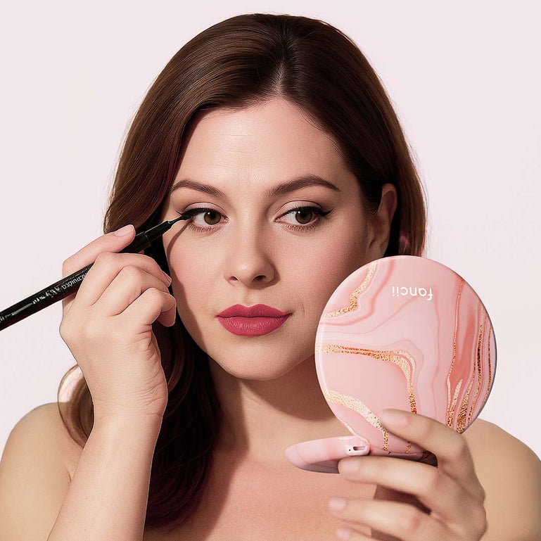 Taylor Lighted Compact Mirror with 10x Magnifying by Fancii & Co. open and lit up held by model in MARBLE ROSÈ