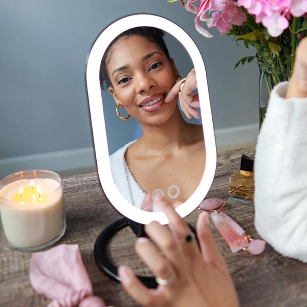 Woman using Fancii's vera lighted vanity to apply skincare in Black