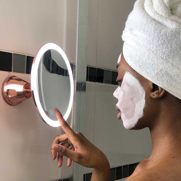 Woman using Fancii Lana 10x magnifying mirror with lights in Rose Gold