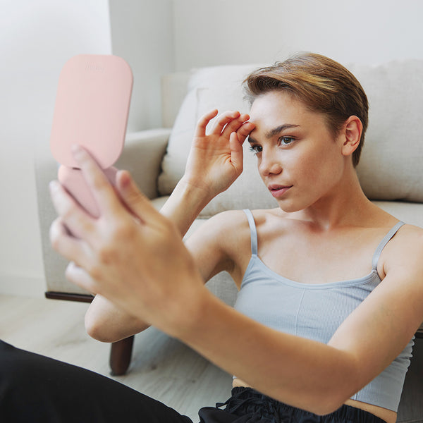 Mica Lighted Compact with built-in powerbank in Strawberry Cream color by Fancii and Co. is being gazed into by a female model.